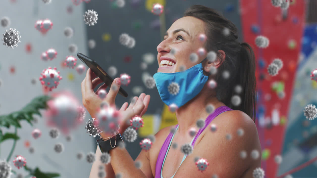 múltiples células de covid-19 flotando contra la mujer en forma caucásica hablando en teléfono inteligente en el gimnasio