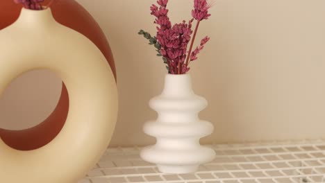 white vase with dried flowers on a shelf