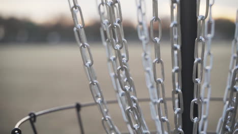 swinging disc golf basket chains in the late evening