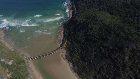 birds eye drone shot of wilderness beach in south africa - drone is circling around the old railway bridge