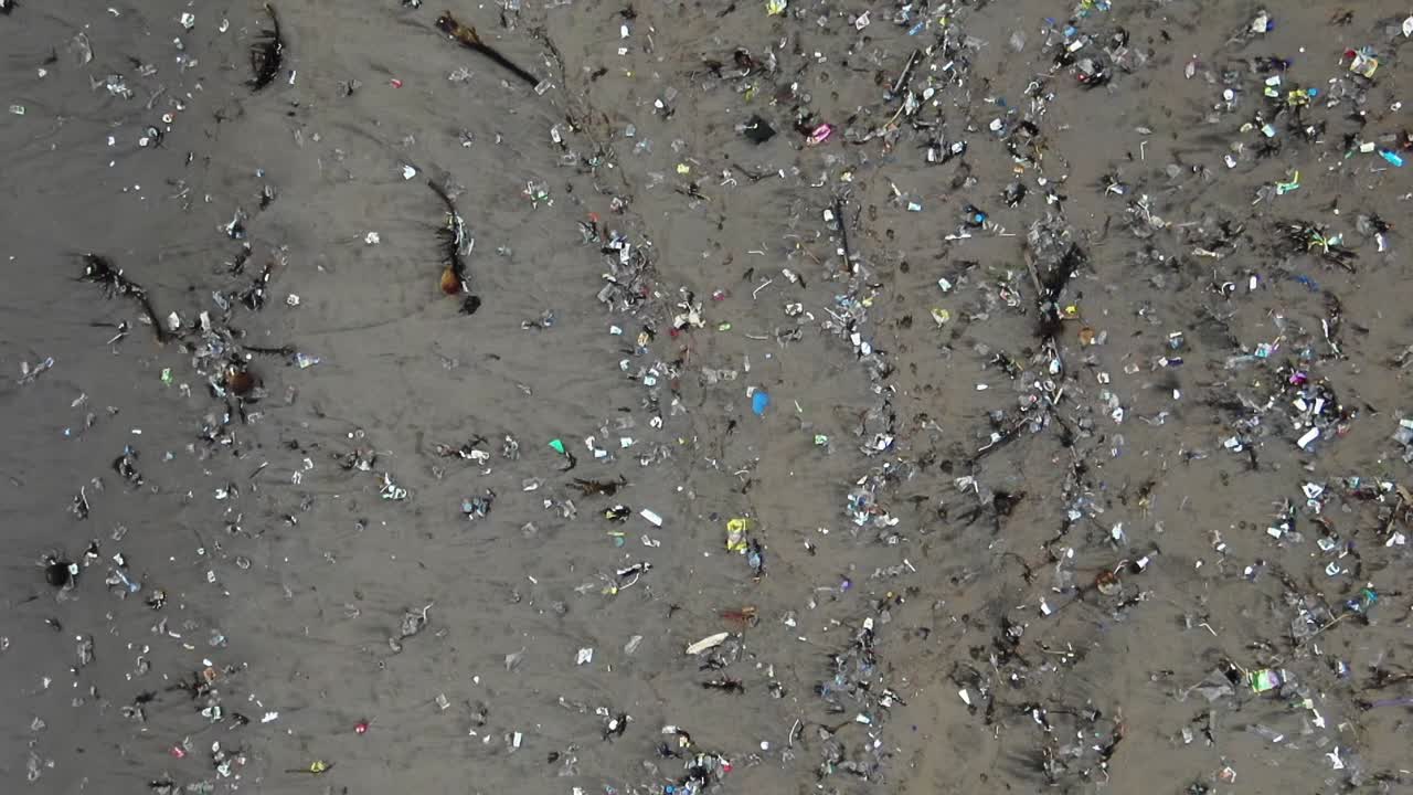 Pulling back aerial shot of an ecological disaster, plastic waste on the beach dying planet