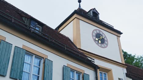 Panning-up-shot,-clock-on-the-facade,-Blutenburg-Castle,-Munich,-Germany