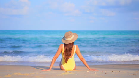 Mujer-Irreconocible-Con-Traje-De-Baño-Amarillo-Sentada-En-Una-Playa-De-Arena-Blanca-Frente-Al-Mar