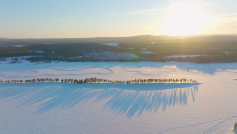 long shadows across snowy lapland golden sunrise drifting racetrack aerial view