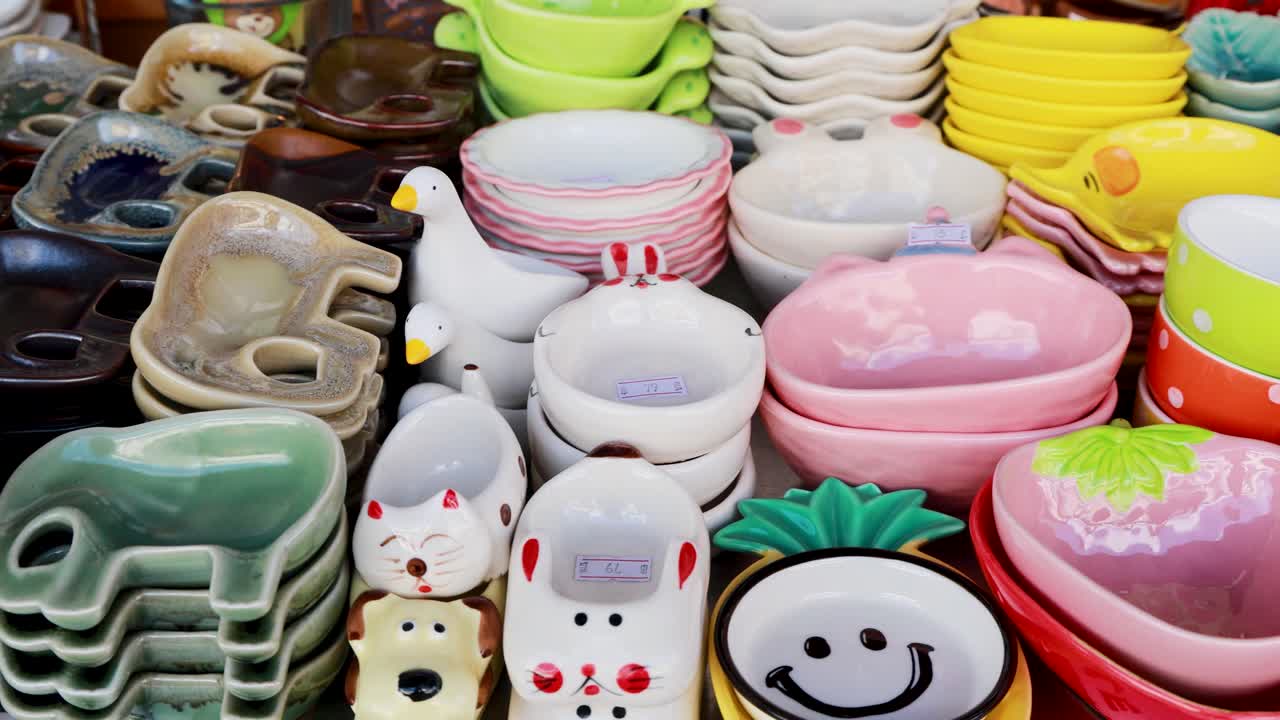 A vibrant array of ceramic dishes and bowls in a Phuket shop, showcasing diverse shapes and colors under bright lighting