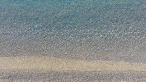 aerial view of calm beach with clear water and pebbles