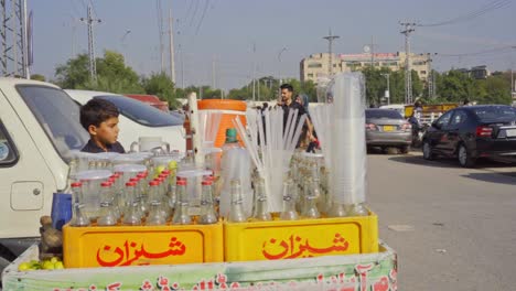 young boy selling lemonade on a busy street in pakistan