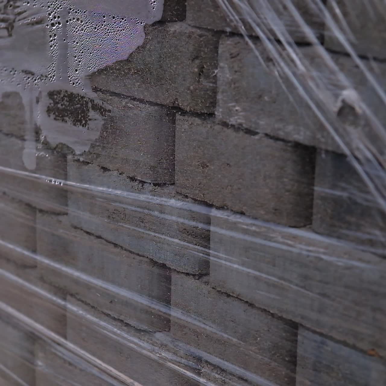 Grey bricks piled in pack and covered with cellophane. Construction materials close up
