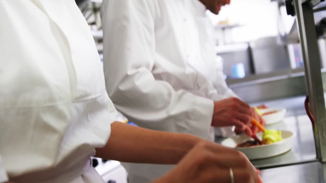 Close-up of team of chefs garnishing dishes