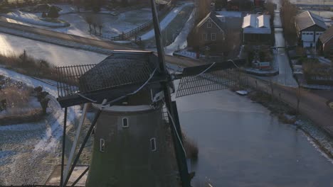 Iconic-landmark-old-windmill-in-Haastrecht,-close-aerial-arc-winter-sunrise