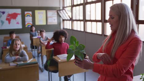 maestra mostrando una maceta de plantas a un grupo de niños en clase en la escuela