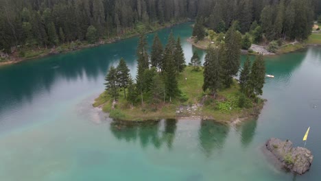 Island-in-middle-of-alpine-lake-with-turquoise-water,-dolly-forward