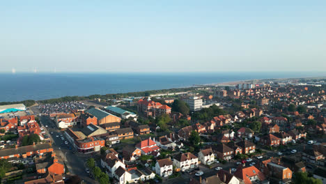 Aerial-video-captures-Skegness,-Lincolnshire's-coastal-charm,-showcasing-its-bustling-tourist-town,-expansive-beach,-and-iconic-pier-on-a-summer-evening