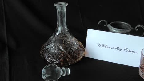 an envelope addressed to whom it may concern is put on a desk beside a whisky decanter