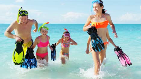 padres y hijas caucásicos buceando en una playa tropical