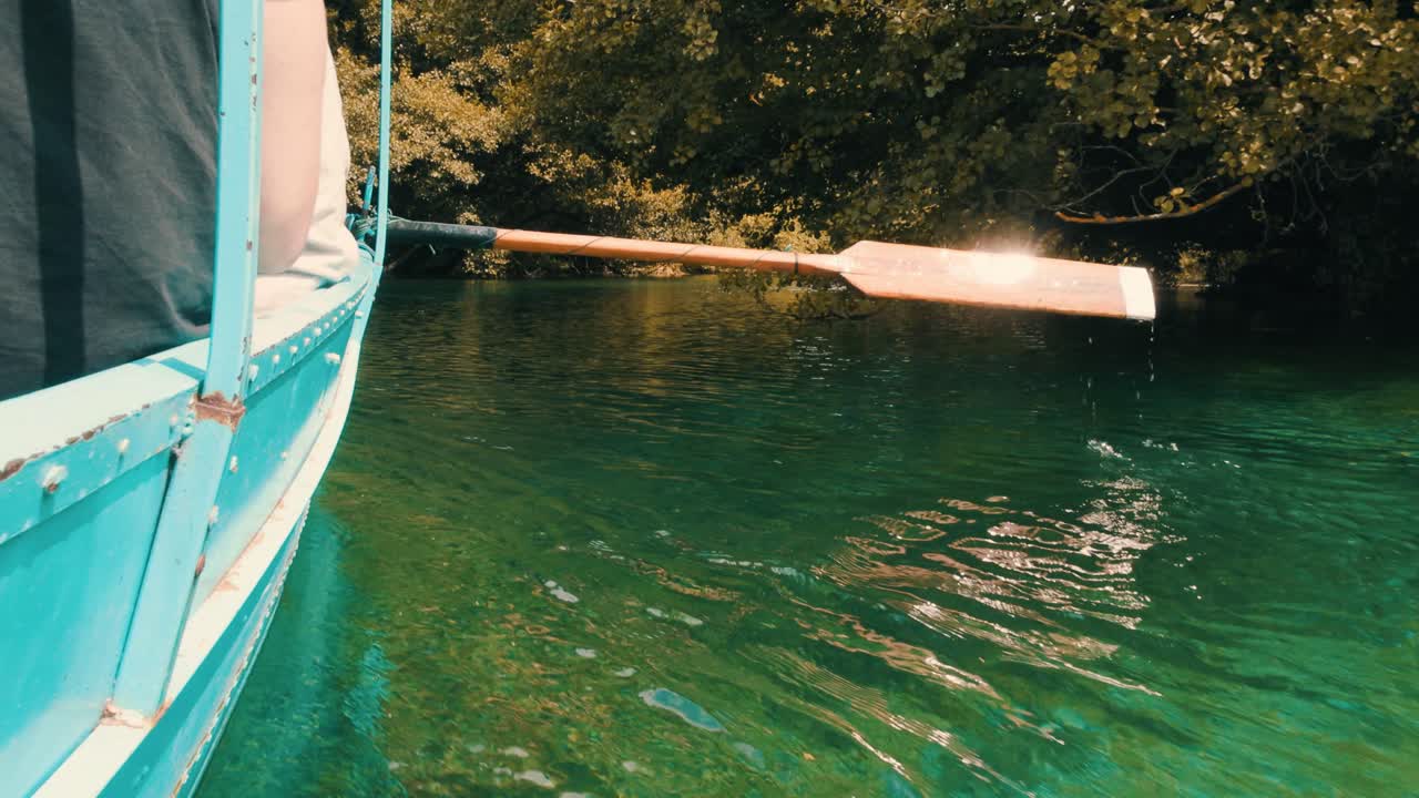 Oar paddling through the crystal clear pristine water of a natural lake transporting people on boat