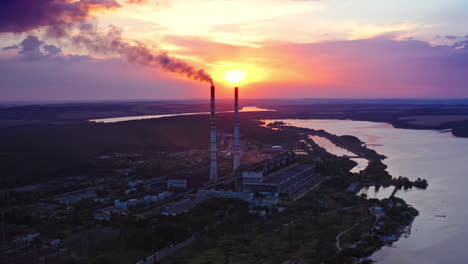 ecological disaster. harmful factory near the river releases dirty emissions at sunset. industry pollute the environment. pipes with smoke on beautiful nature background.