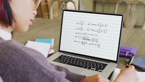 asian female student having class on laptop video call with mathematical equations in slow motion