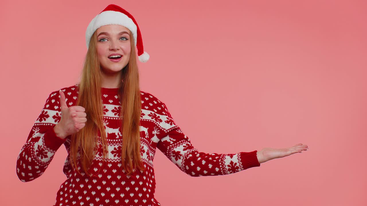 mujer lleva suéter de año nuevo rojo ciervo mostrando los pulgares hacia arriba y señalando en el espacio de publicidad en blanco