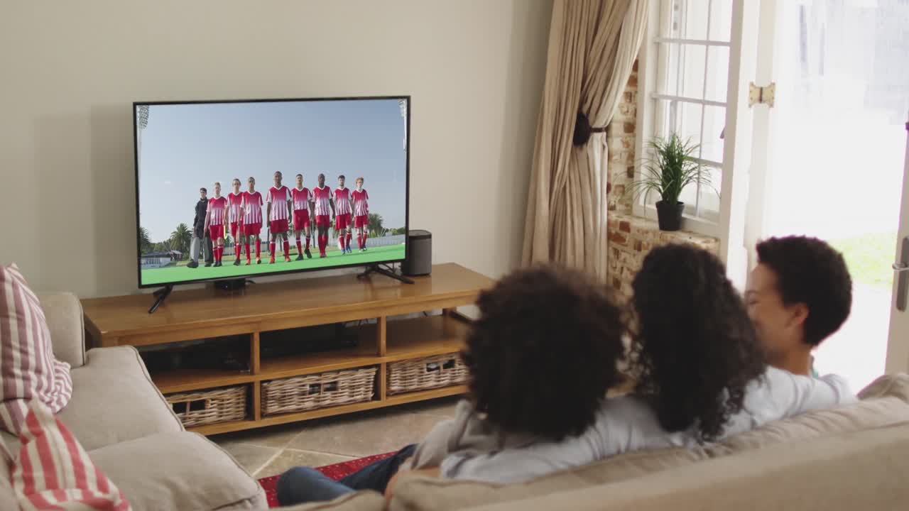 Famiglia felice seduta a casa insieme che guarda un evento sportivo in TV