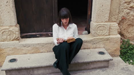 woman reading the bible on the entrance steps of the church