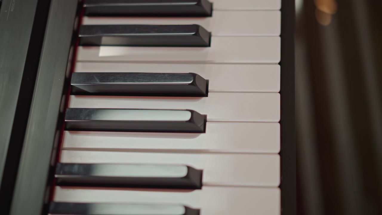 Vista dall'alto dei tasti di una tastiera di pianoforte digitale con rivestimento in feltro rosso, durante una sessione di pratica in aula. Luce naturale intensa, esercizio di scale per studenti, con implicita guida dell'istruttore, diesis neri nitidi e movimento ripetitivo delle dita.