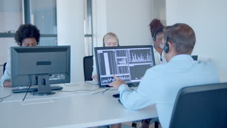 team of financial brokers in headsets working in office