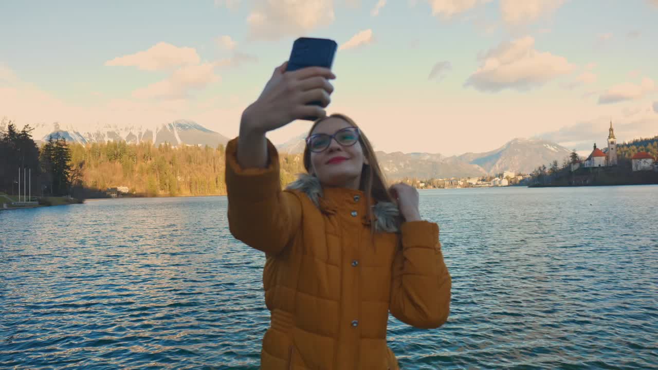 video en 4k de una hermosa joven caucásica tomando una foto selfie en un destino turístico muy famoso, bled, eslovenia.