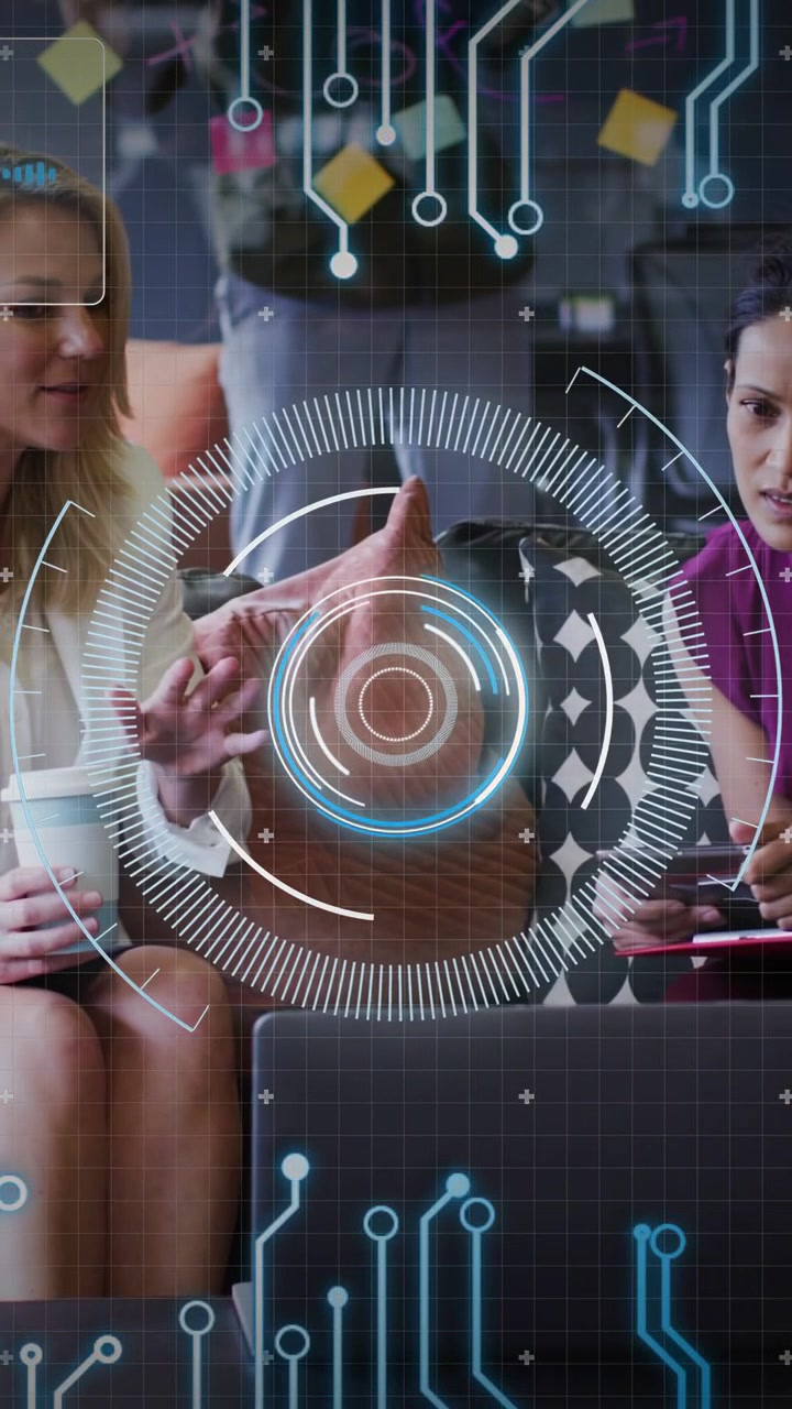 Vertical video: Two women leaning in with laptop as HUD appears, tapping tablet, testing app