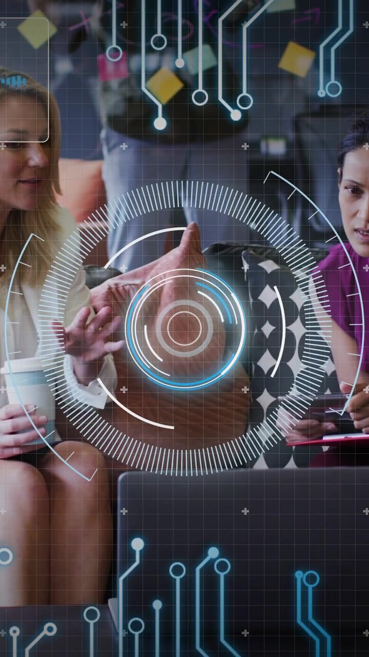 Vertical video: Two women leaning in with laptop as HUD appears, tapping tablet, testing app