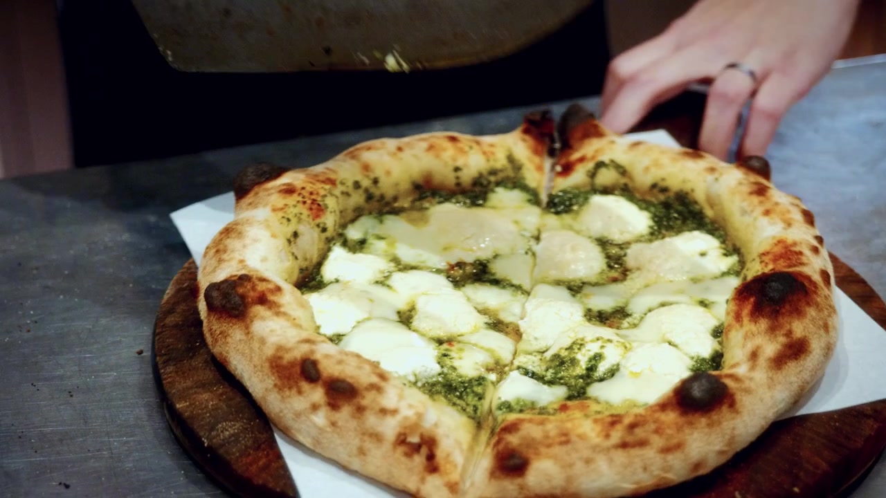 Autentico processo di preparazione della pizza in una pizzeria tradizionale italiana, con lo chef che taglia la pizza