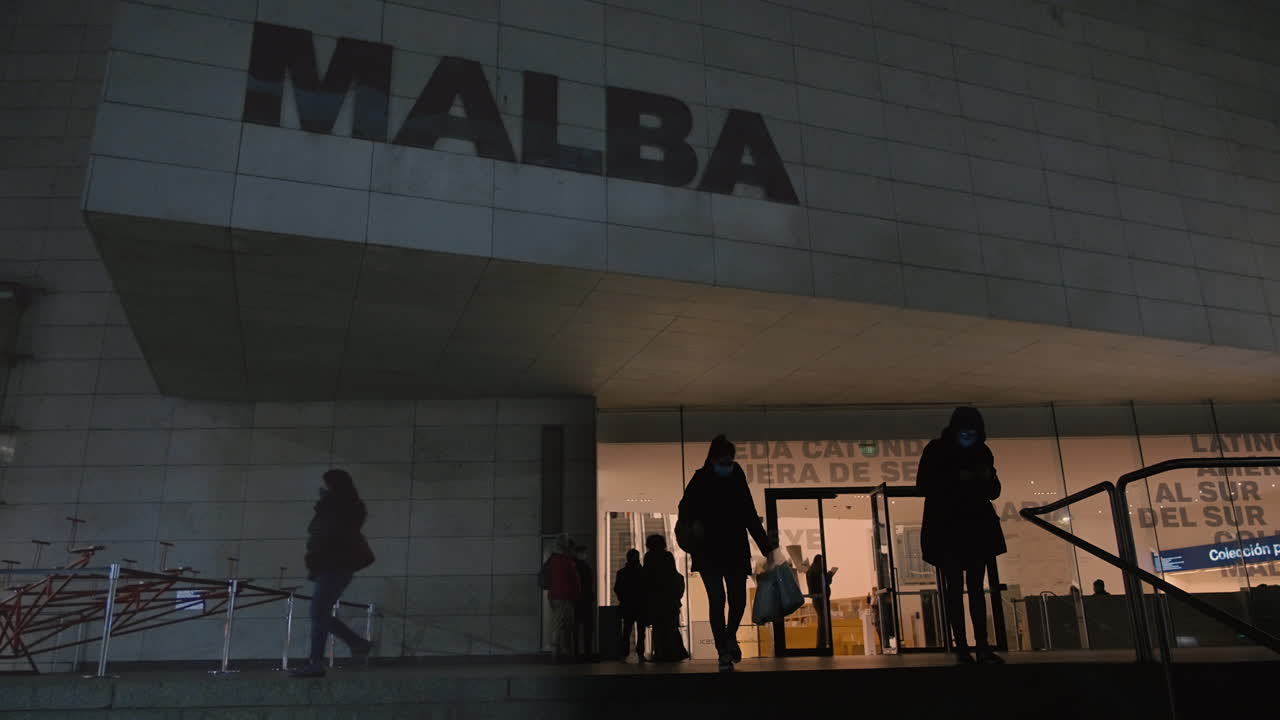 Folk går ind og ud af MALBA Museum om natten