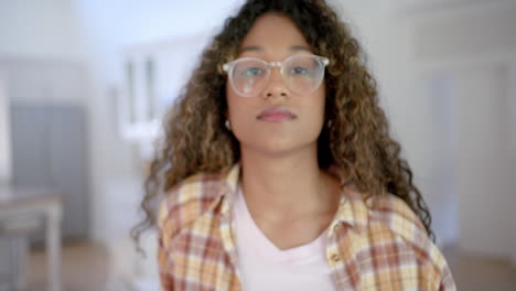 Portrait-of-happy-biracial-female-teenager-with-curly-hair-at-home,-slow-motion