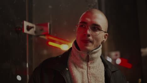 portrait of a bald man with glasses at night under neon lights