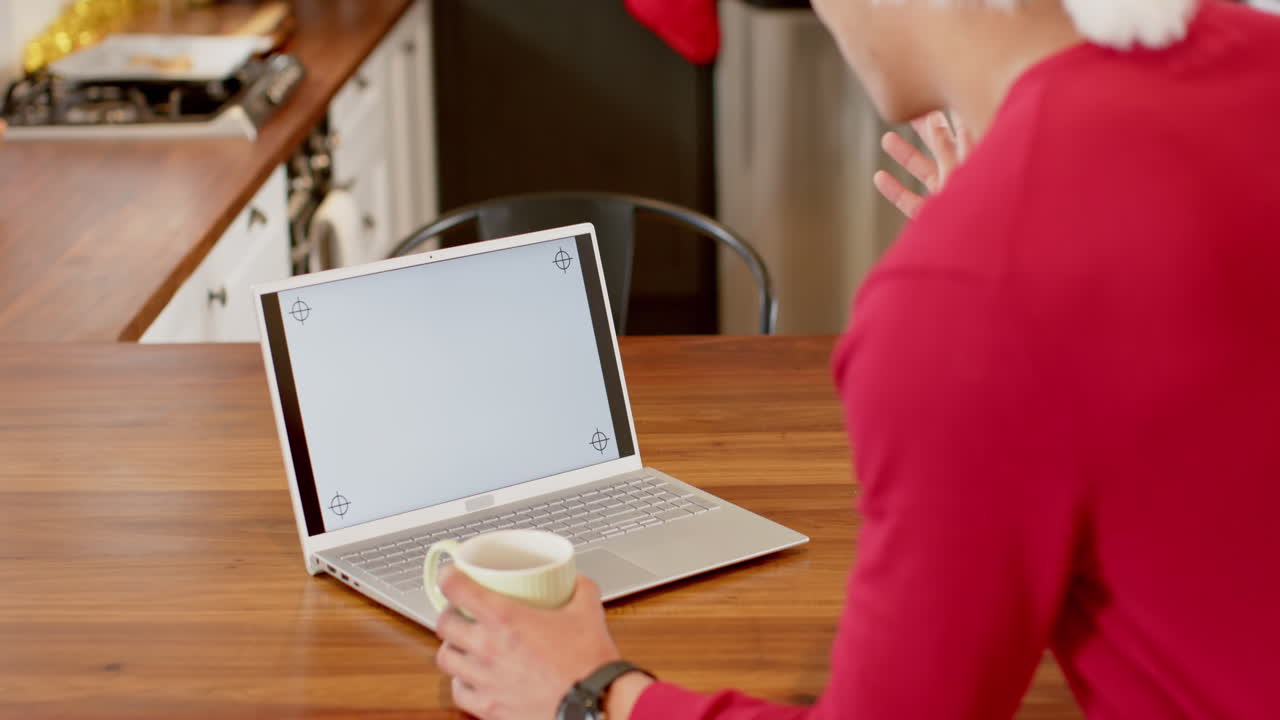 산타클로스 모자를 입은 두 인종의 남자가 크리스마스에서 노트북을 사용하고 집에서 느린 동작, 복사 공간