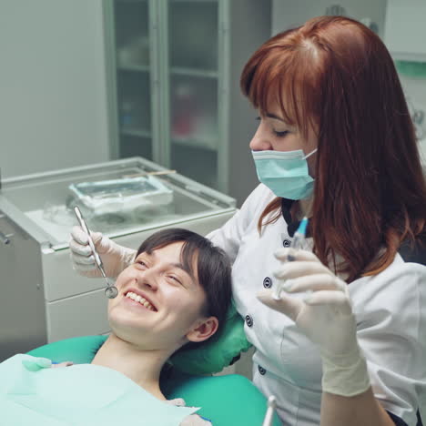 female dentist in dental office talking with female patient and preparing for treatment.