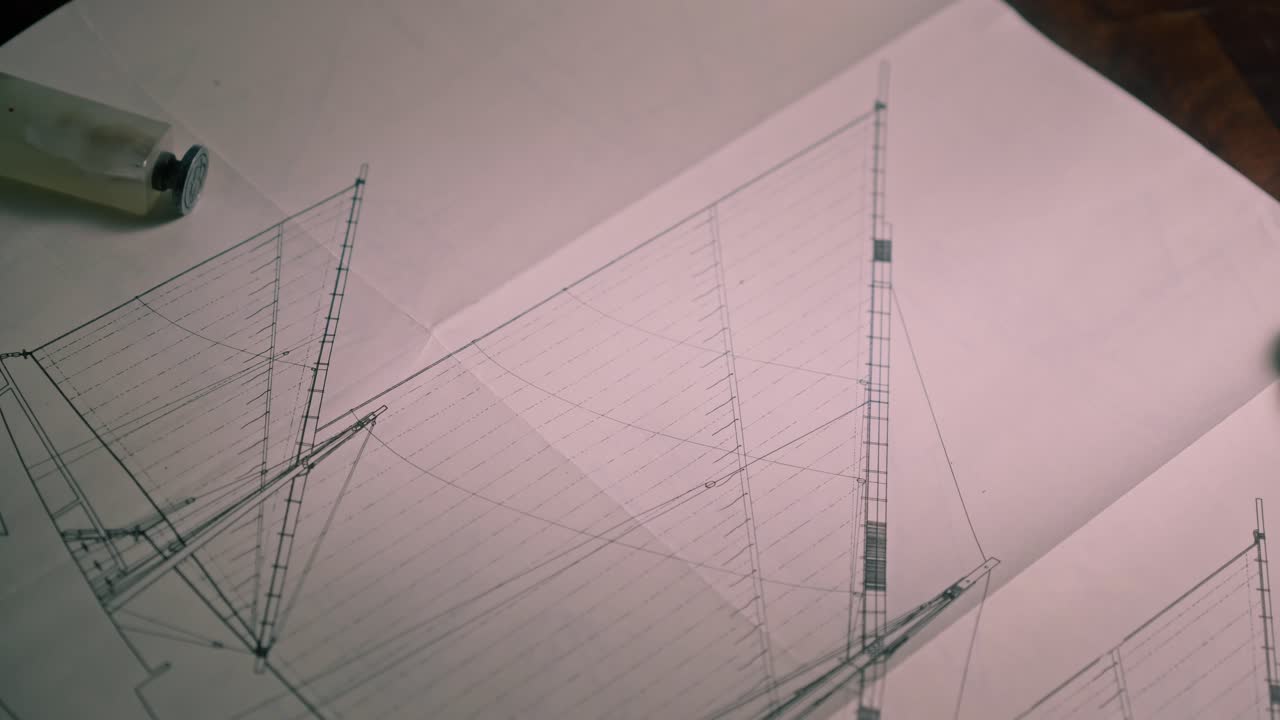 Naval Draftsman lays ink pens on sailing ship design Blueprint. charts