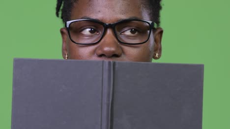 young beautiful african businesswoman covering face with book