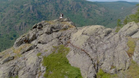 a young woman is sitting on the edge of a mountain cliff