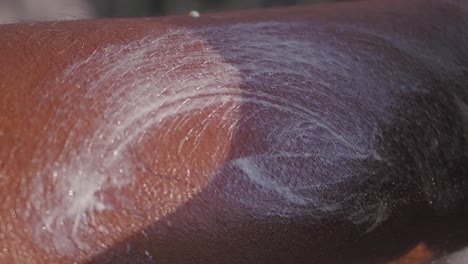 close up of a person's hand applying sunscreen to their arm