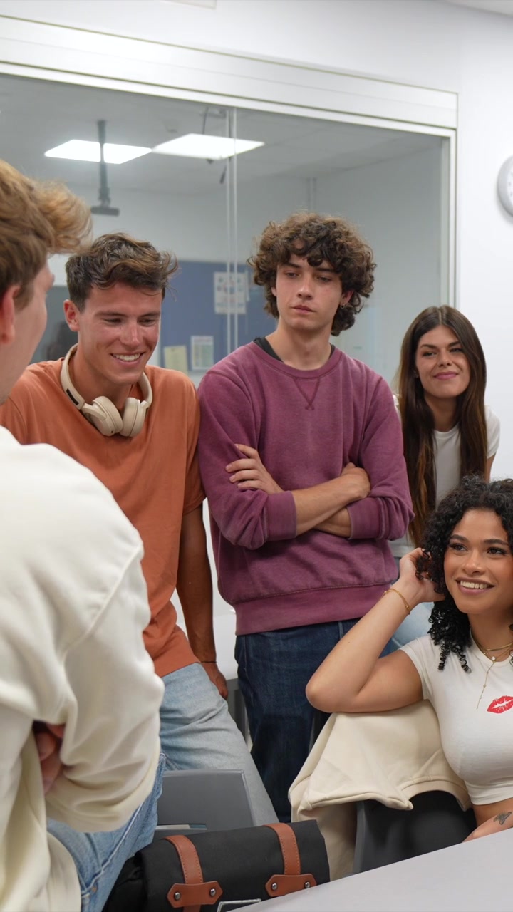 Estudiantes jóvenes felices hablando y sonriendo en un aula.