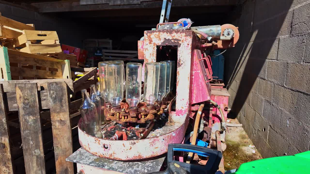 Antiga máquina de engarrafamento rotativa ou enchedora de garrafas em um local de armazenamento de fazenda rural.