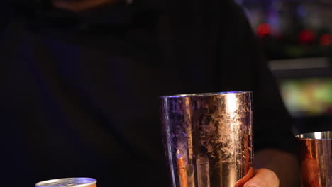 bartender pours ice from scoop into cocktail shaker, ice cubes tumble into martini shaker, slow motion close up 4k