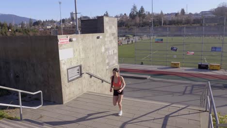 young fit girl running up steps exercising outdoors wide shot