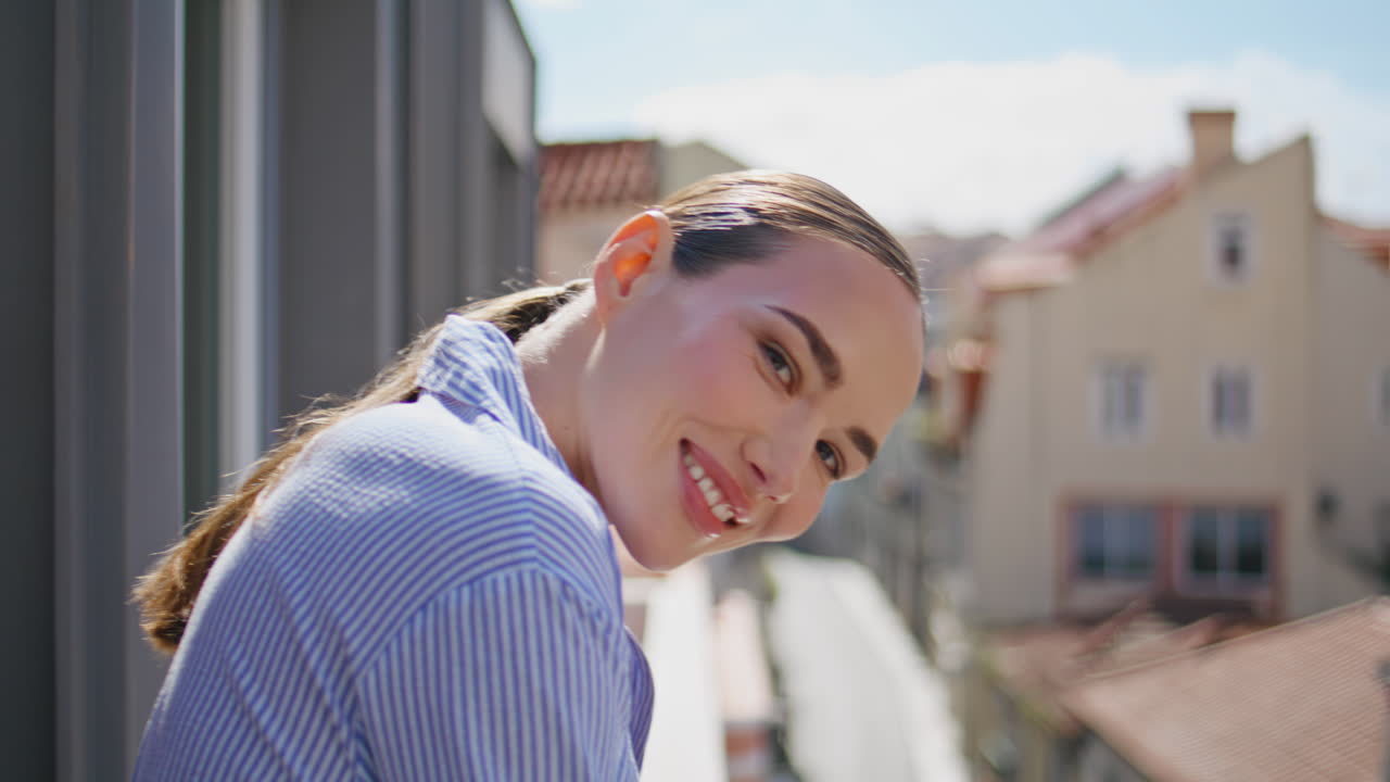 Carefree woman standing cityscape rooftop looking camera in front sky closeup