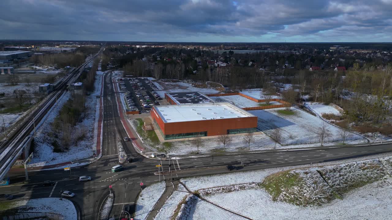 Indoor swimming pool with solar panels surrounded by snow and suburban homes in Falkensee Germany. Unique aerial view flight fly reverse drone