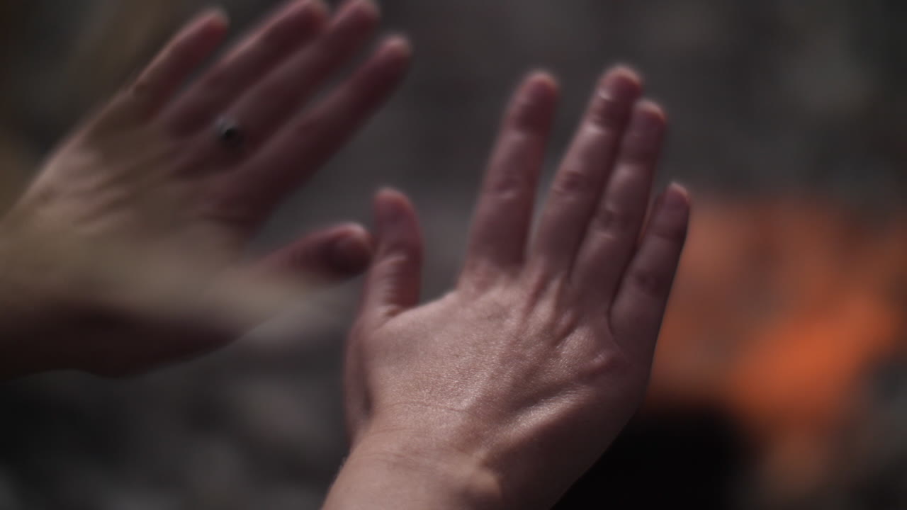 Woman warming her hands over a bonfire