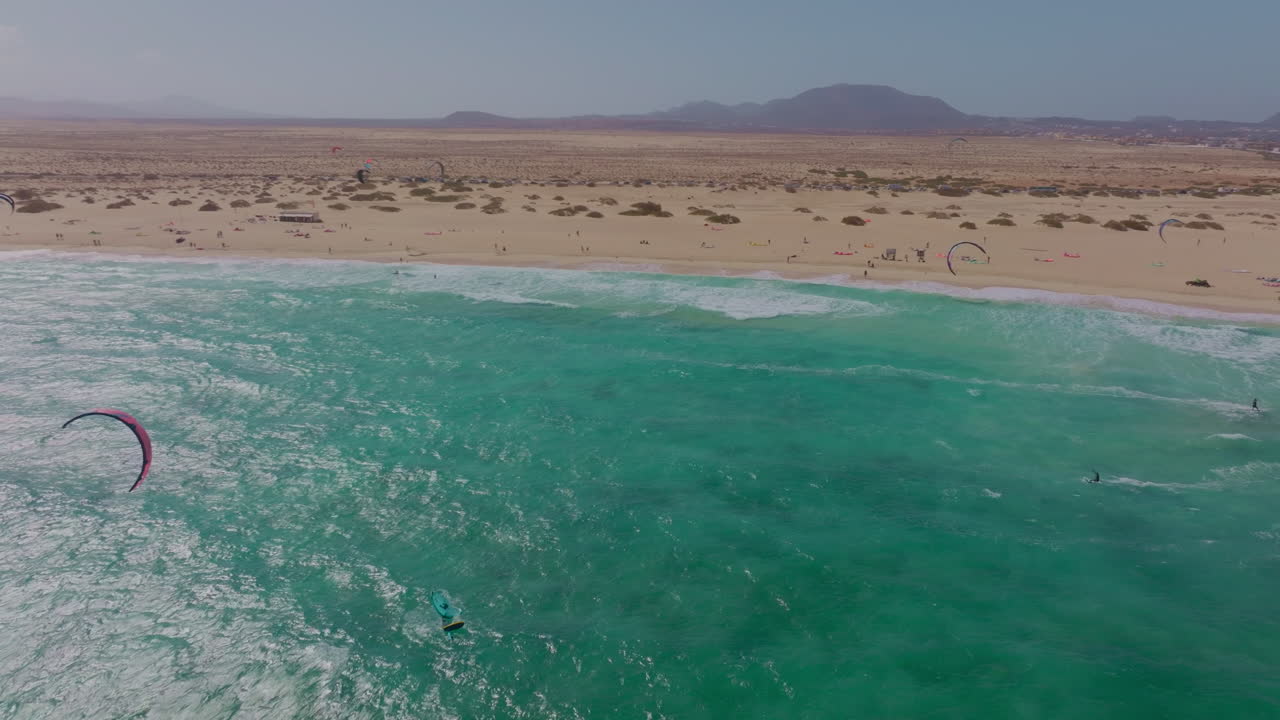 Breathtaking views of Fuerteventura with Lobos Island, Red Flag Beach, kite surfers, sunsets, volcanoes, sand dunes, and wingfoilers in the Canary Islands’ golden light.
