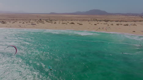 breathtaking views of fuerteventura with lobos island, red flag beach, kite surfers, sunsets, volcanoes, sand dunes, and wingfoilers in the canary islands’ golden light.
