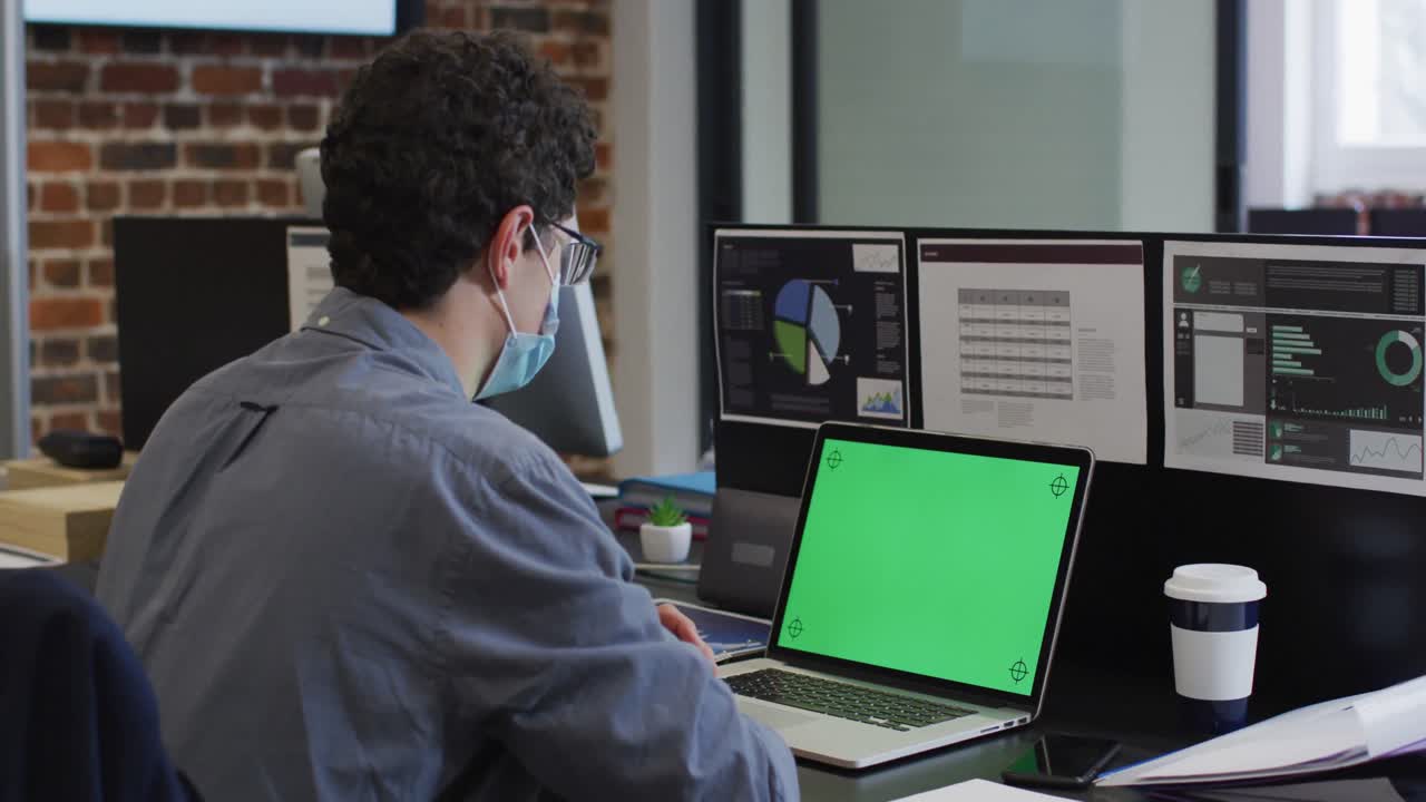 hombre con máscara facial usando una computadora portátil en la oficina